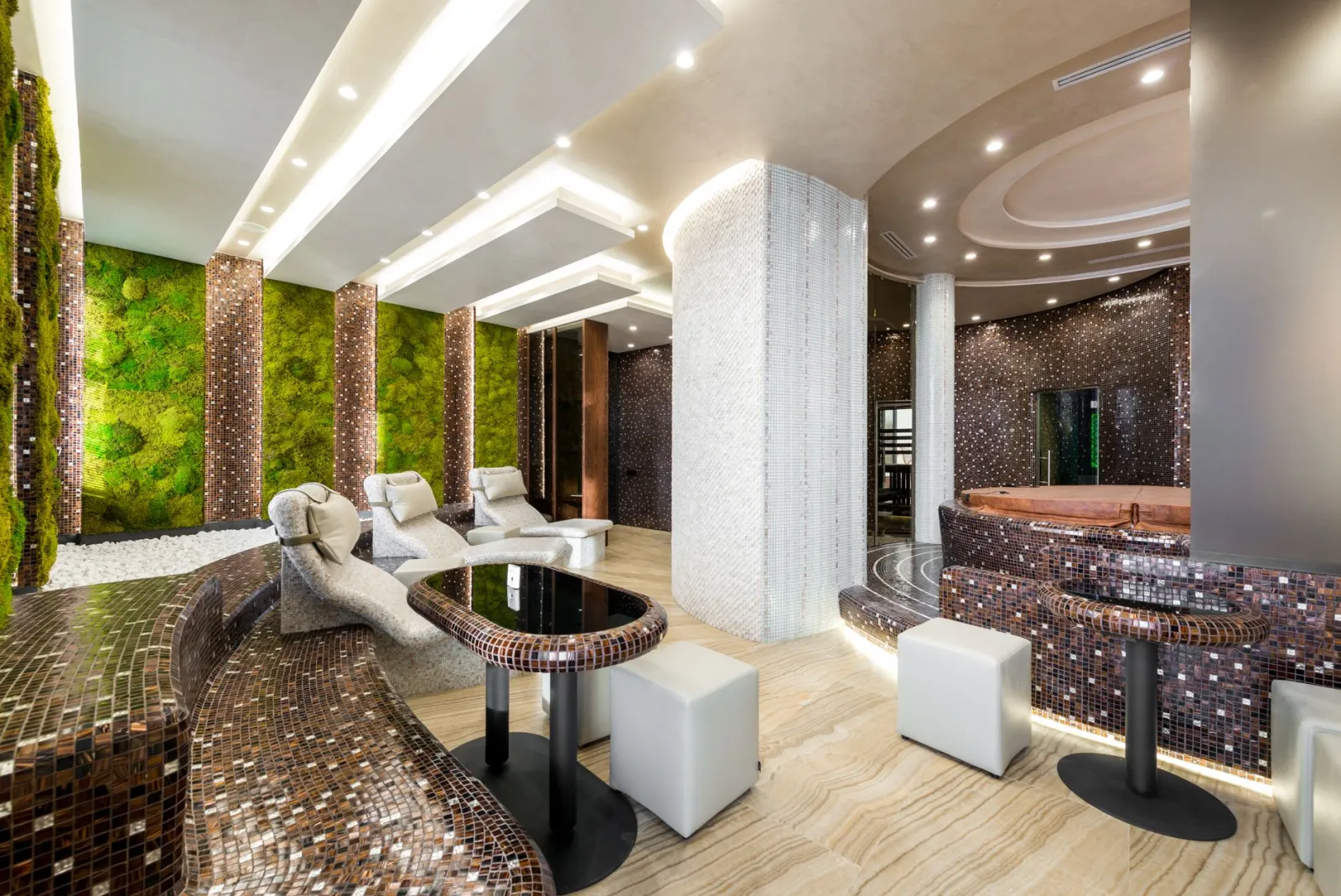 Comfortable heated tiled chaise lounges and bathtubs in modern luxurious spa center decorated with creative illumination and fresh green plants on walls